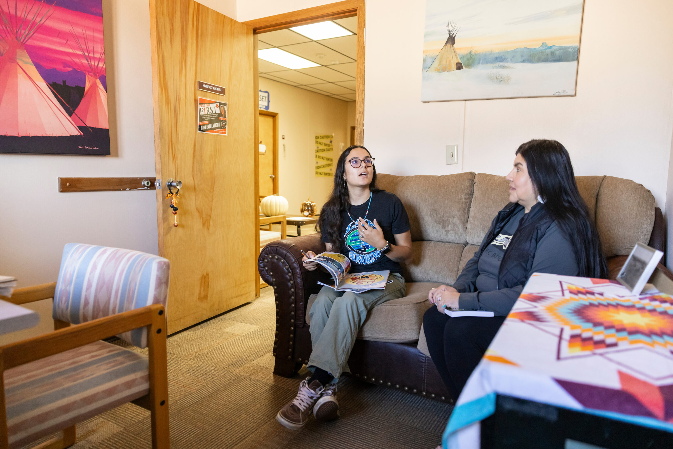 Student and advisor talking in an office on a college campus.