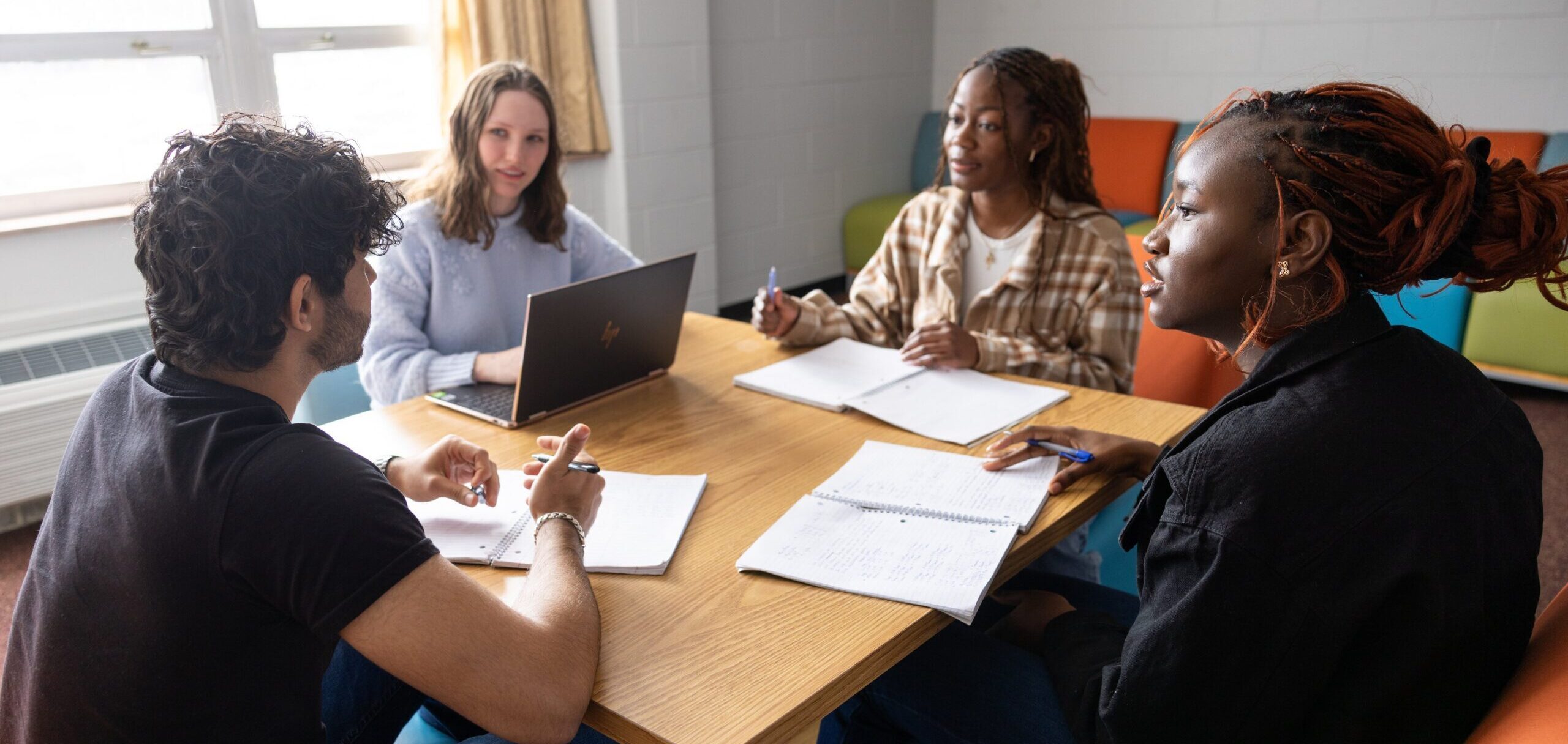 Group of students studying together in a residence hall common area on a college campus.