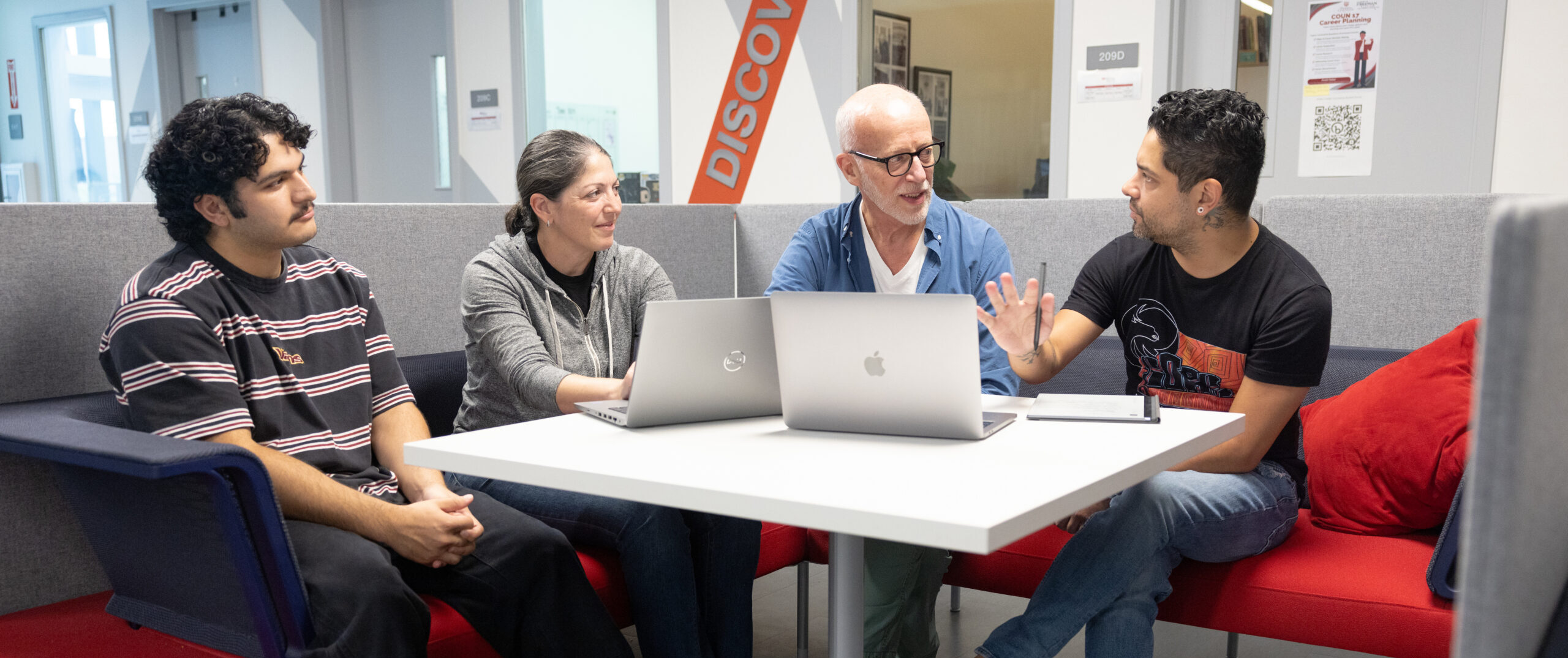 Multiethnic group of faculty meeting in a common area on a college campus.